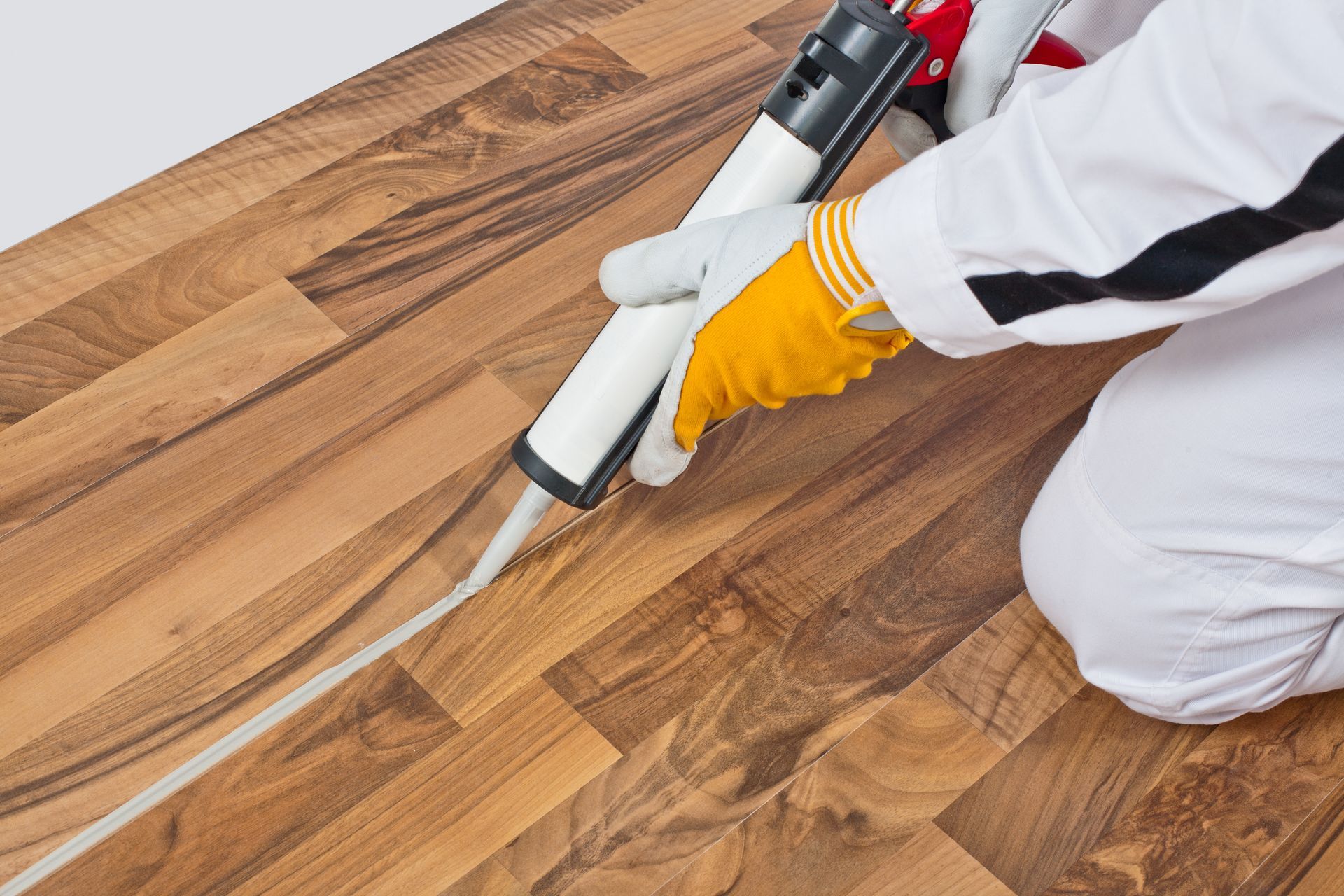 A person is applying sealant to a wooden floor.