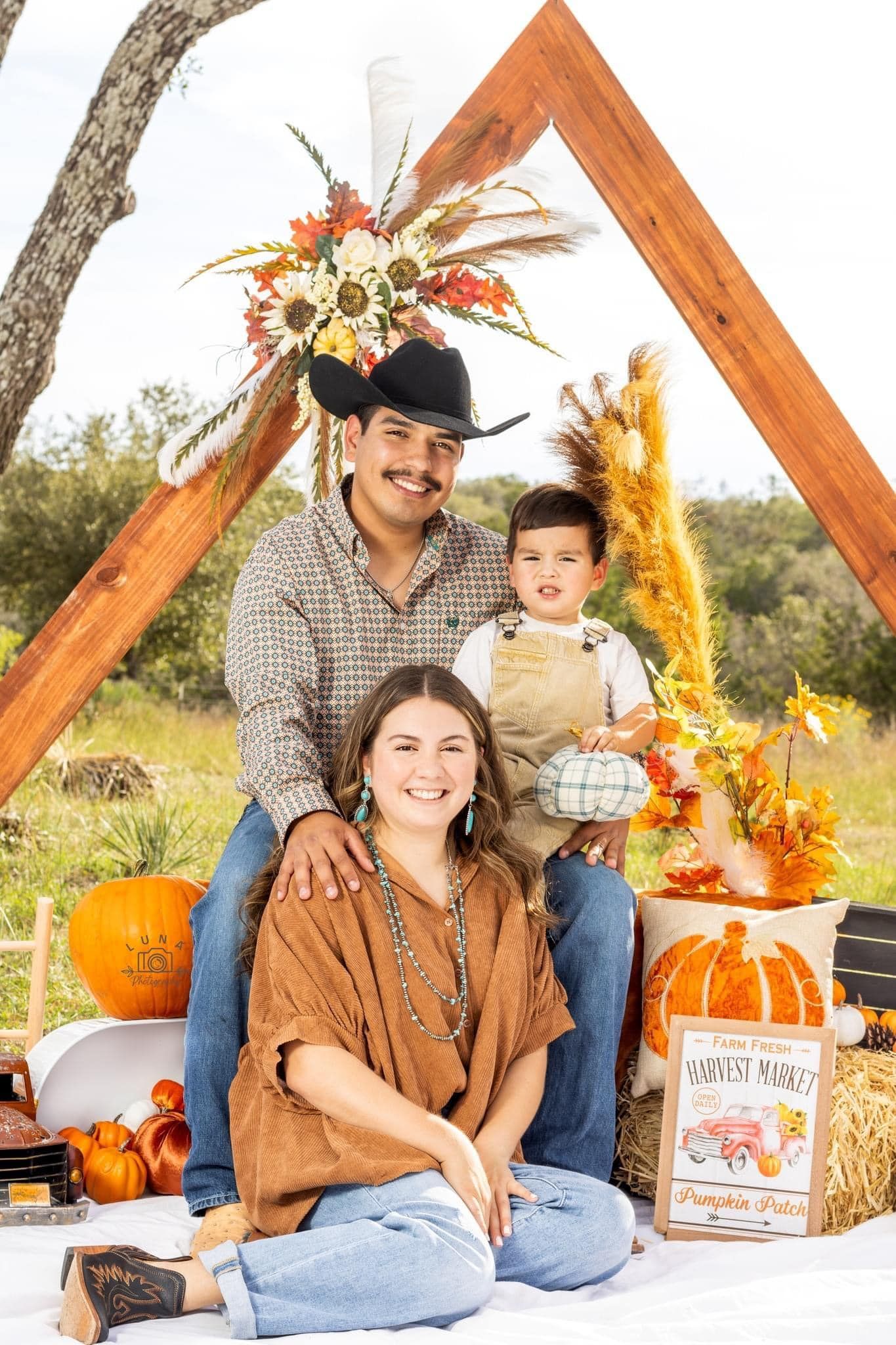 A family is posing for a picture in a field with pumpkins.
