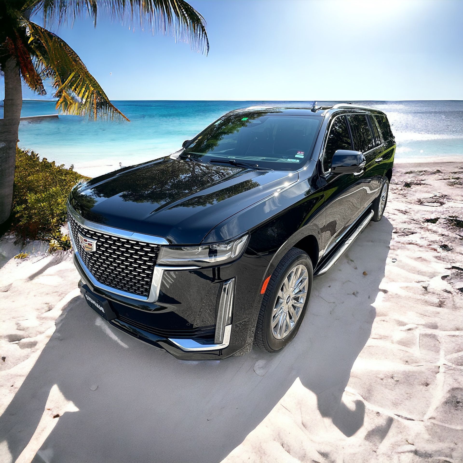 A black suv is parked on a sandy beach near the ocean