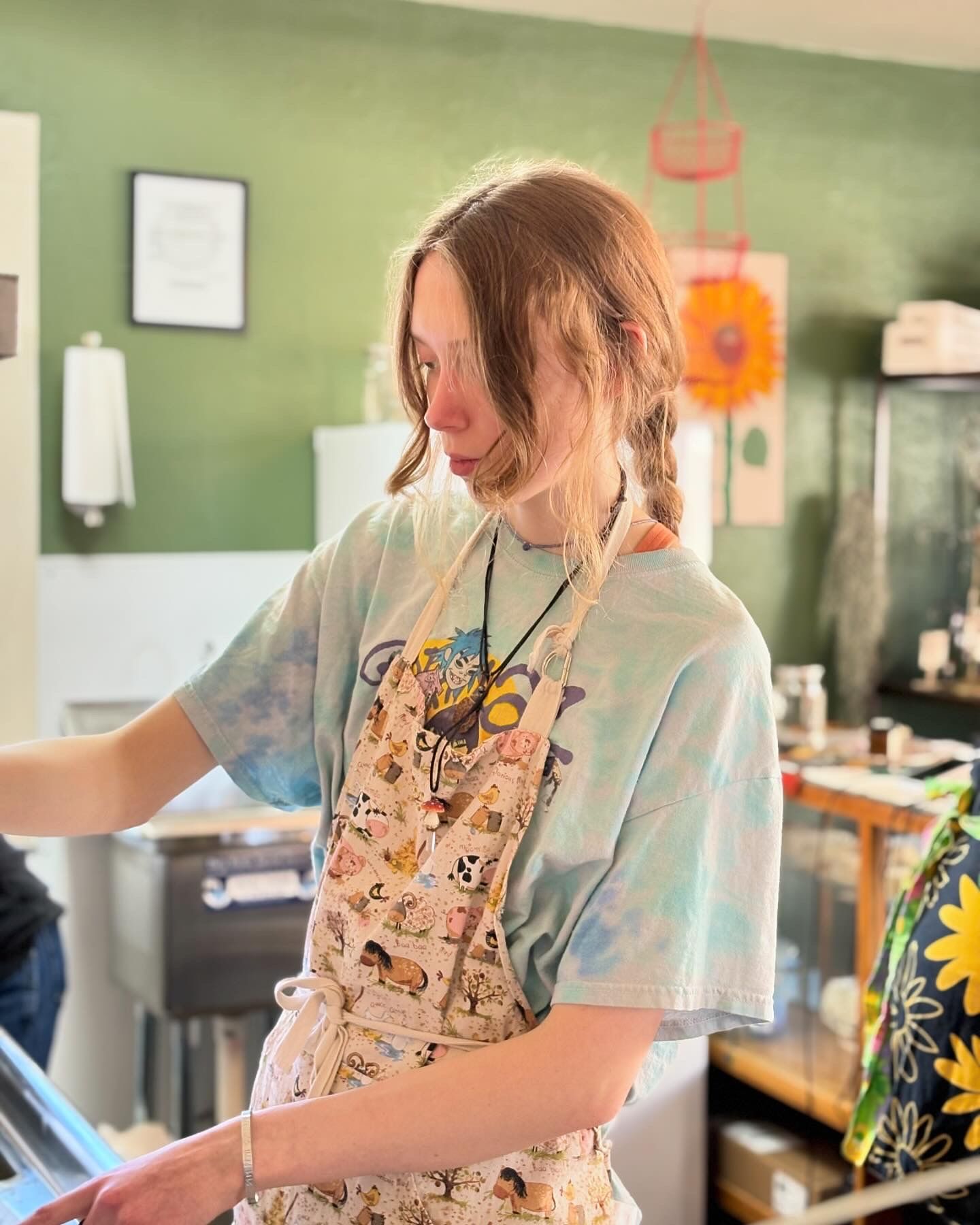 A woman wearing an apron is standing in a kitchen.