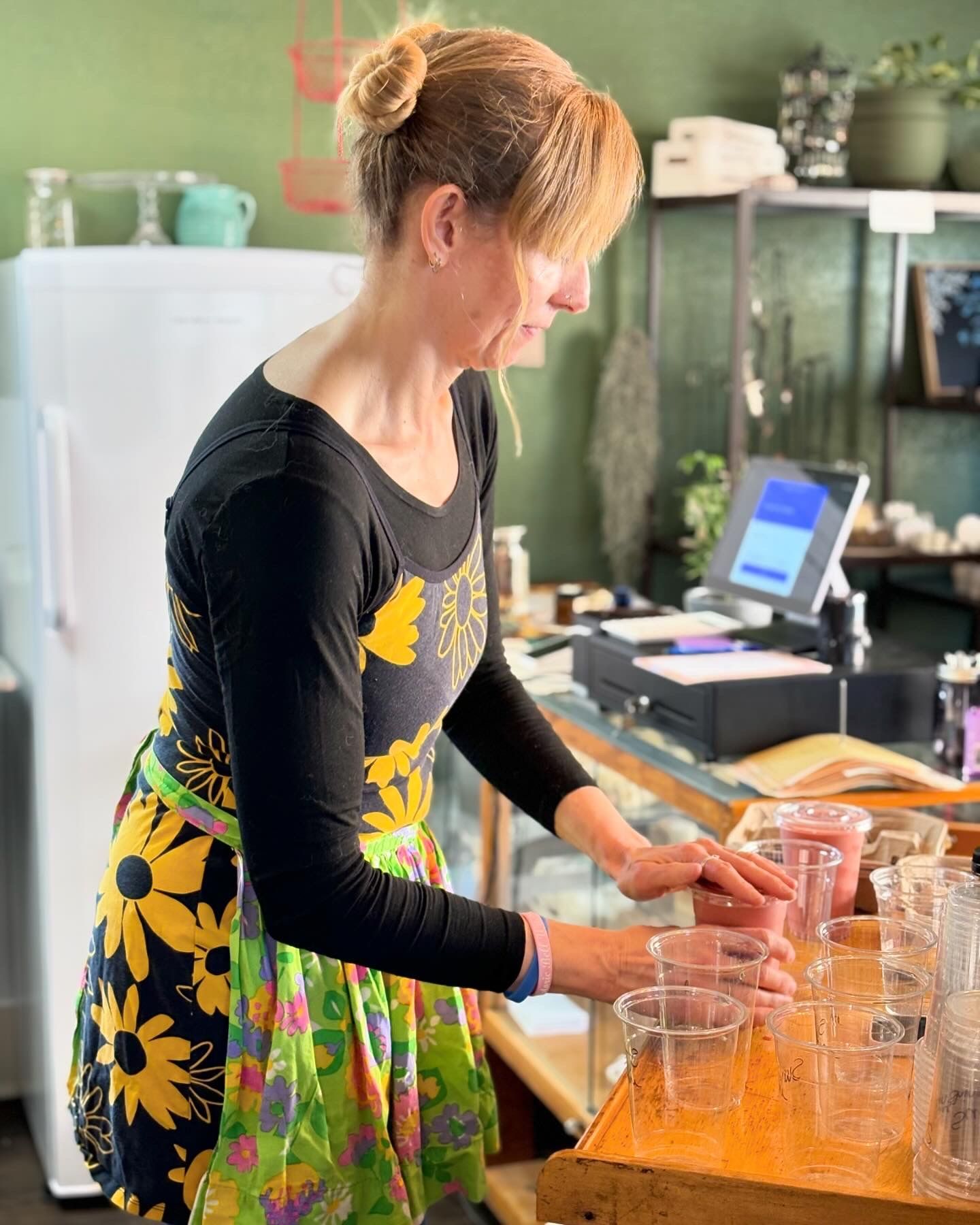 A woman in a colorful dress is standing at a counter in a kitchen.