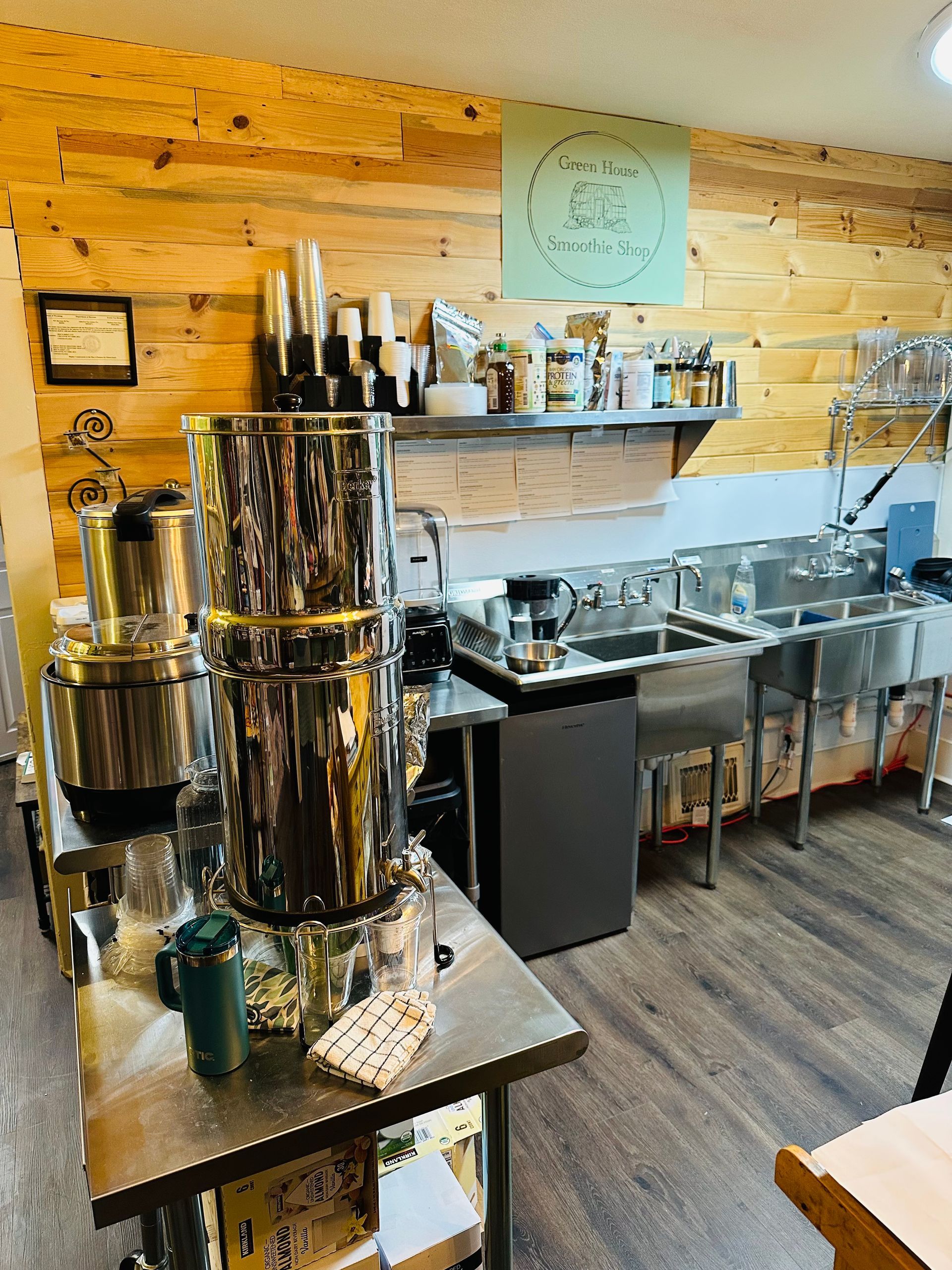 A kitchen with a lot of stainless steel appliances and a wooden wall.