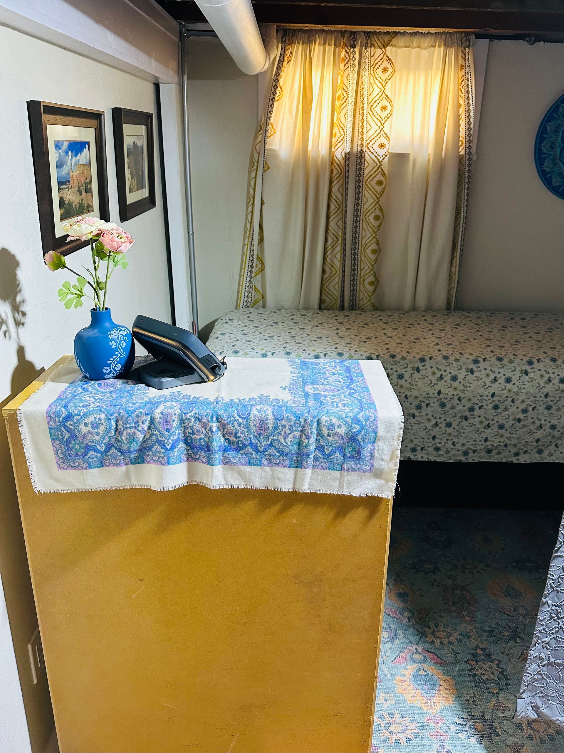 A room with two beds and a vase of flowers on a table.