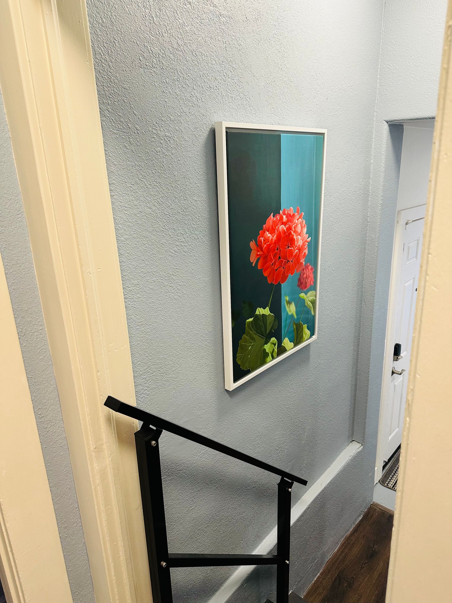 A picture of a flower is hanging on a wall next to a staircase.