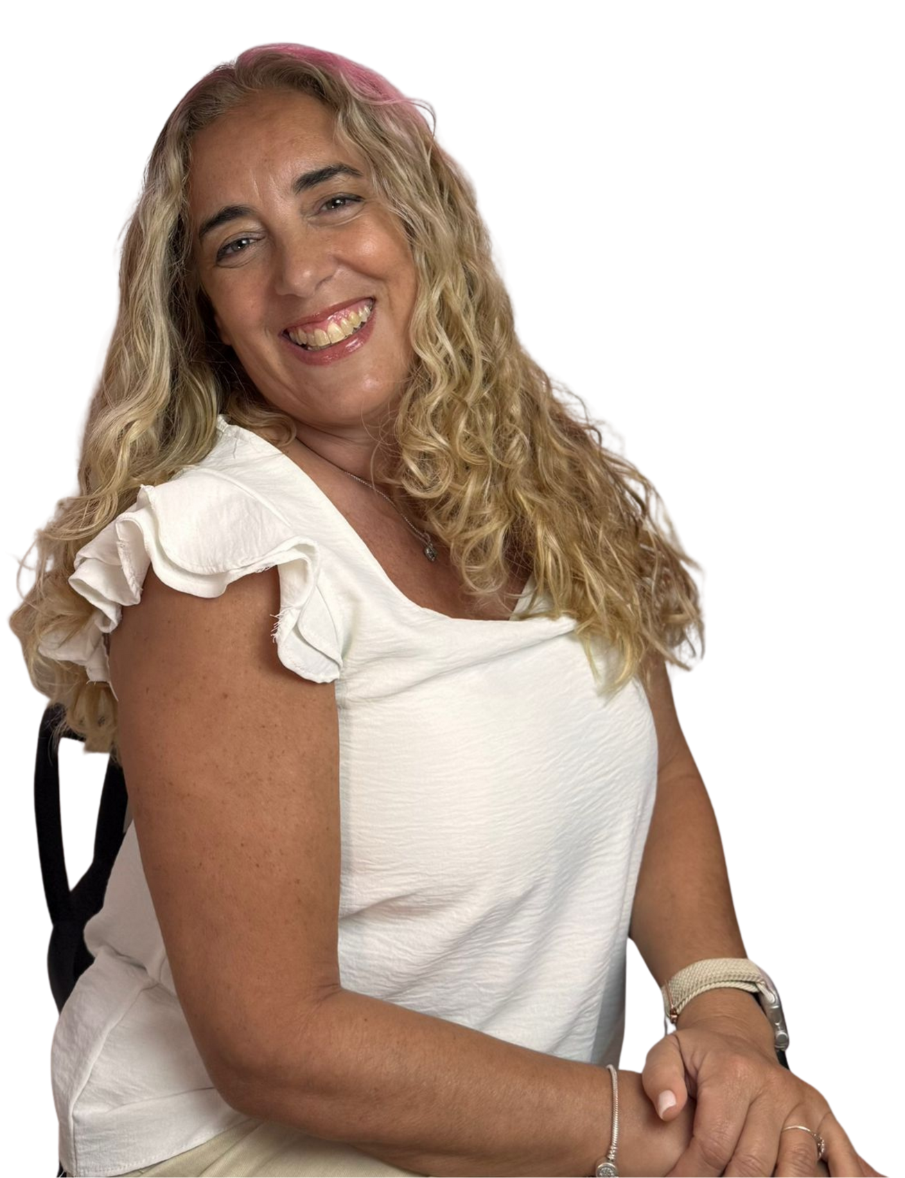 Mujer con cabello rubio largo y ondulado sonríe, vestida con una blusa blanca y pulseras, sentada.