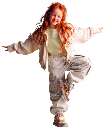 Niña de pelo largo y rojo, vestida con chaqueta y pantalones blancos, equilibrada sobre una pierna.