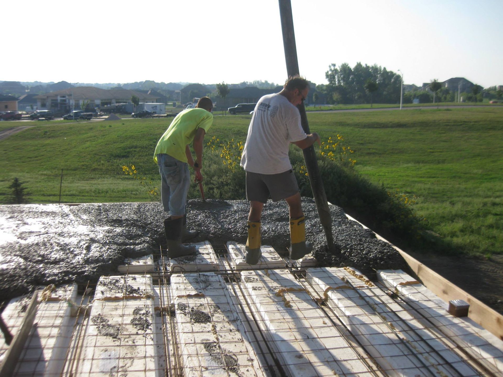 Two men are working on a concrete floor in a field