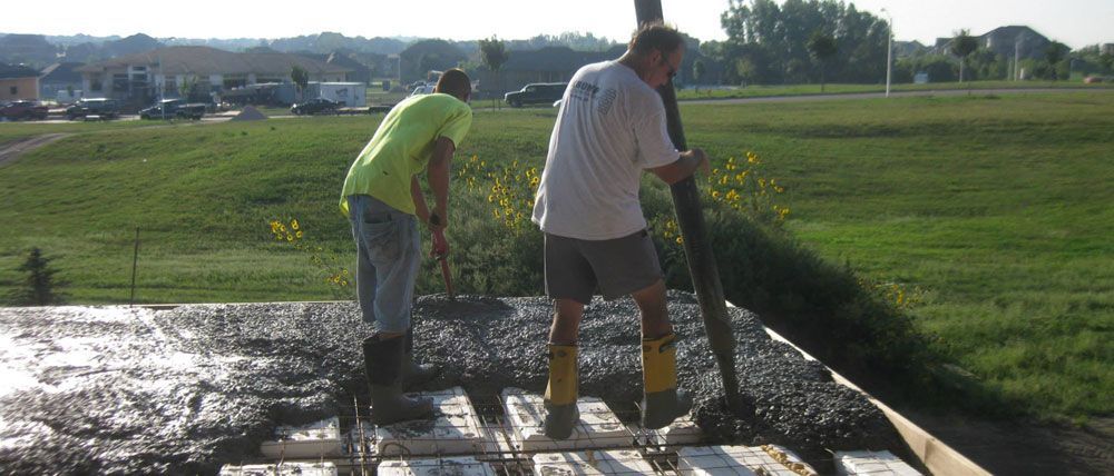 Two men are working on a concrete floor in a field