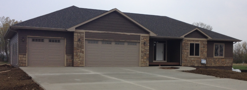A large house with two garage doors and a concrete driveway.