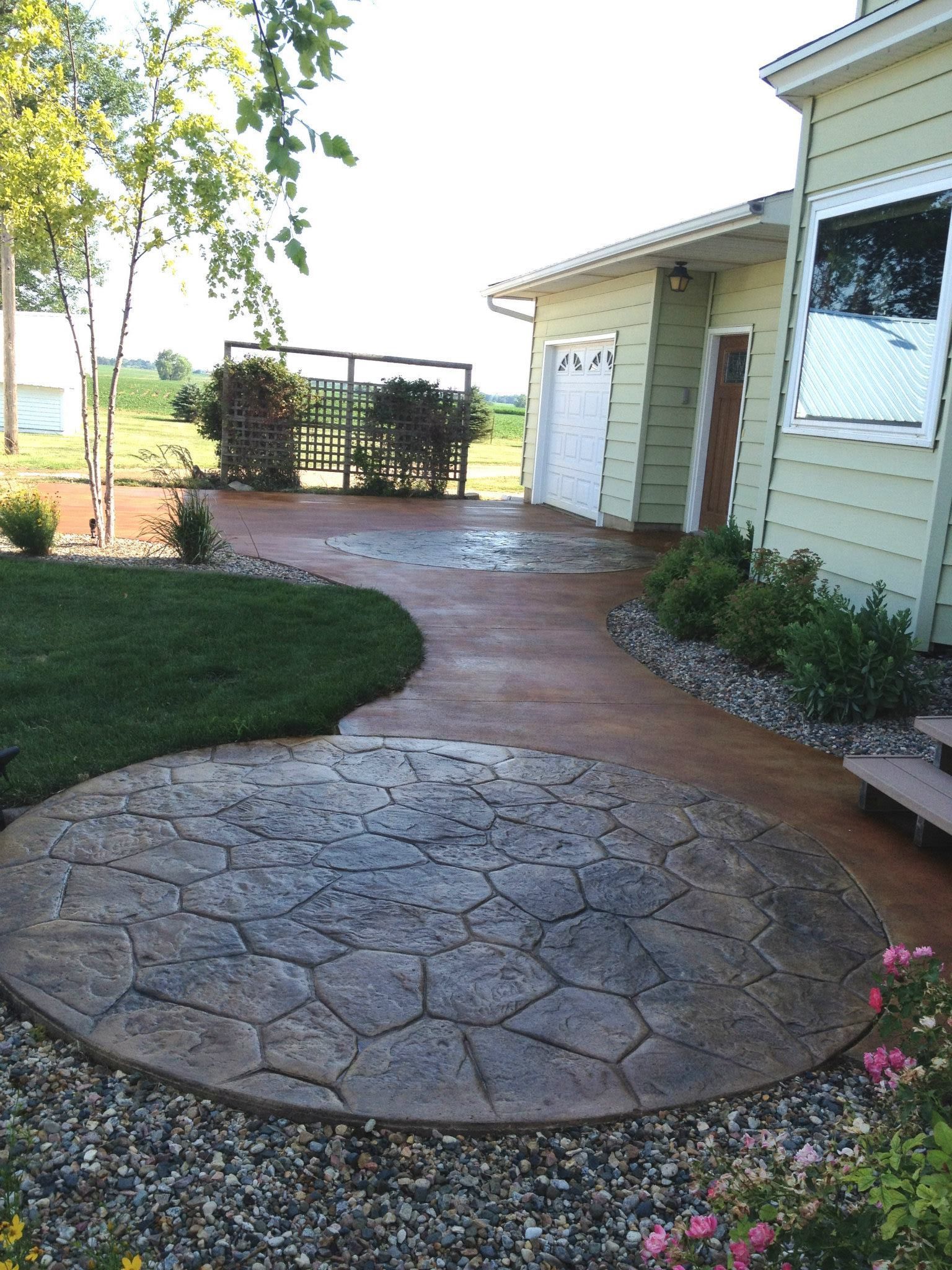 A walkway leading to a house with a circular patio in front of it