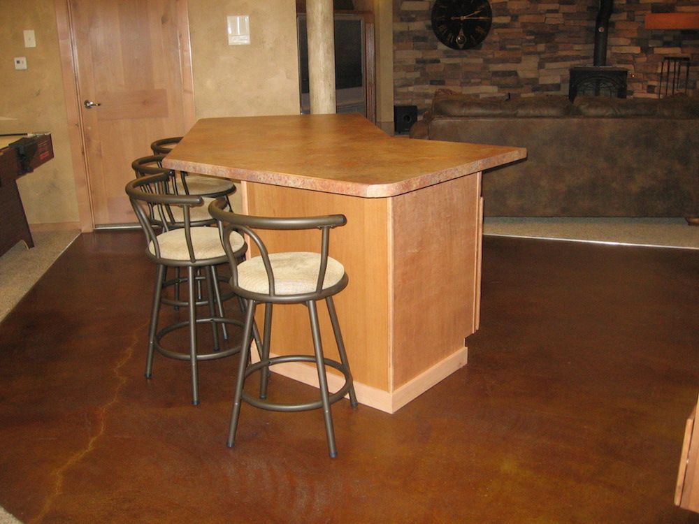 A bar with stools and a pool table in the background