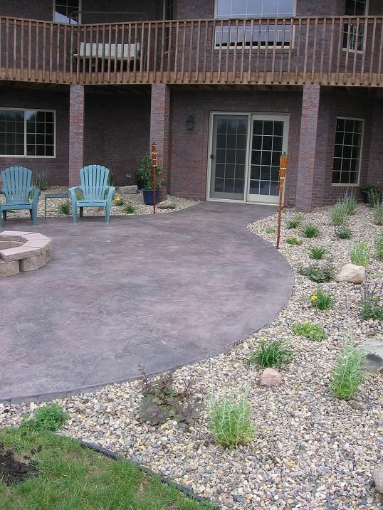 A patio with blue chairs and a fire pit in front of a house