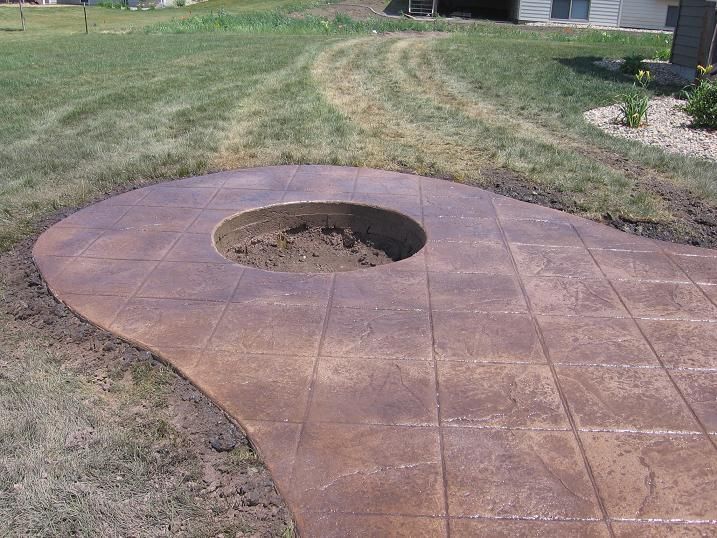 A concrete patio with a fire pit in the middle of it