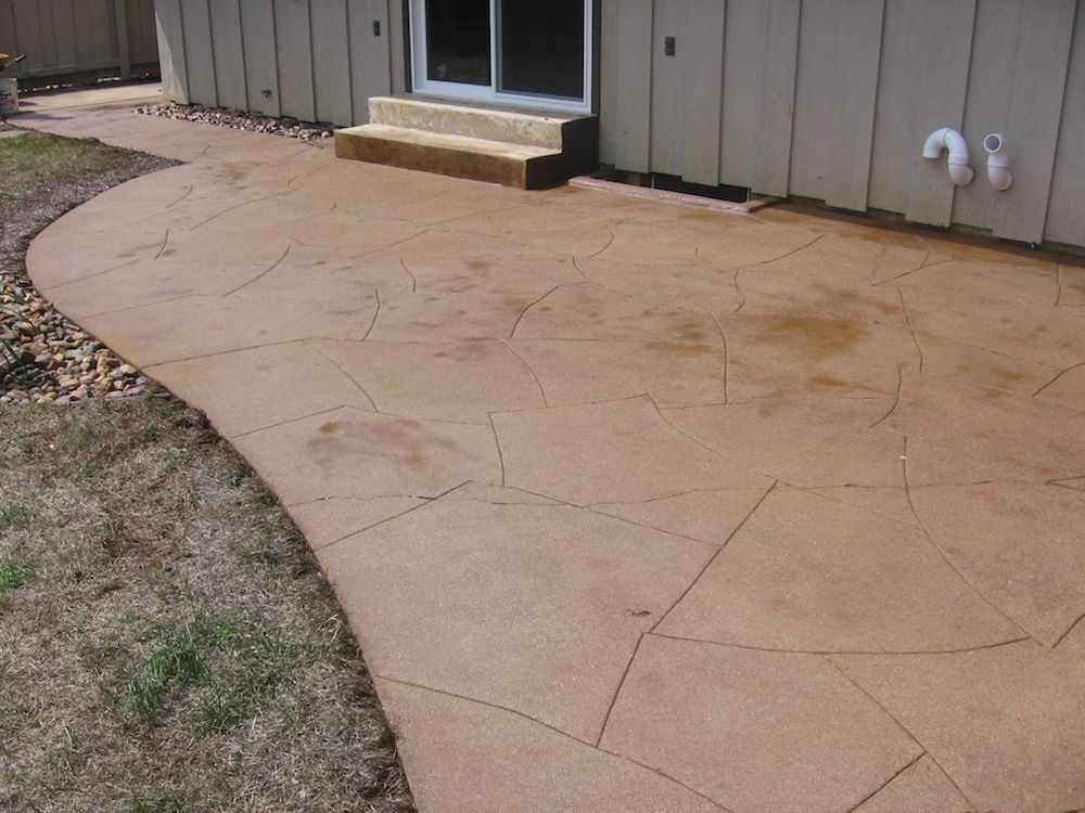 A concrete walkway leading to a house with a sliding glass door