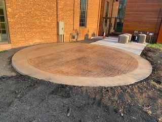 A circular concrete walkway is being built in front of a brick building.
