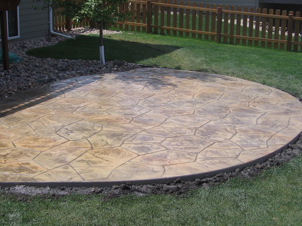 A circular concrete patio with a wooden fence in the background