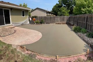 A concrete patio is being built in the backyard of a house.