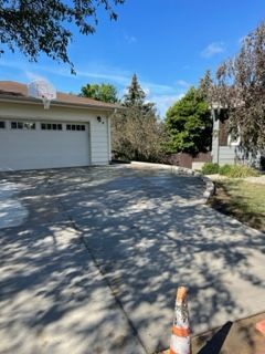 A driveway leading to a house with a basketball hoop on top of it.