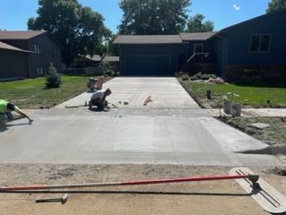 A man is working on a concrete driveway in front of a house.