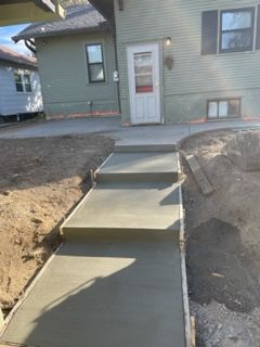 A concrete walkway is being built in front of a house.