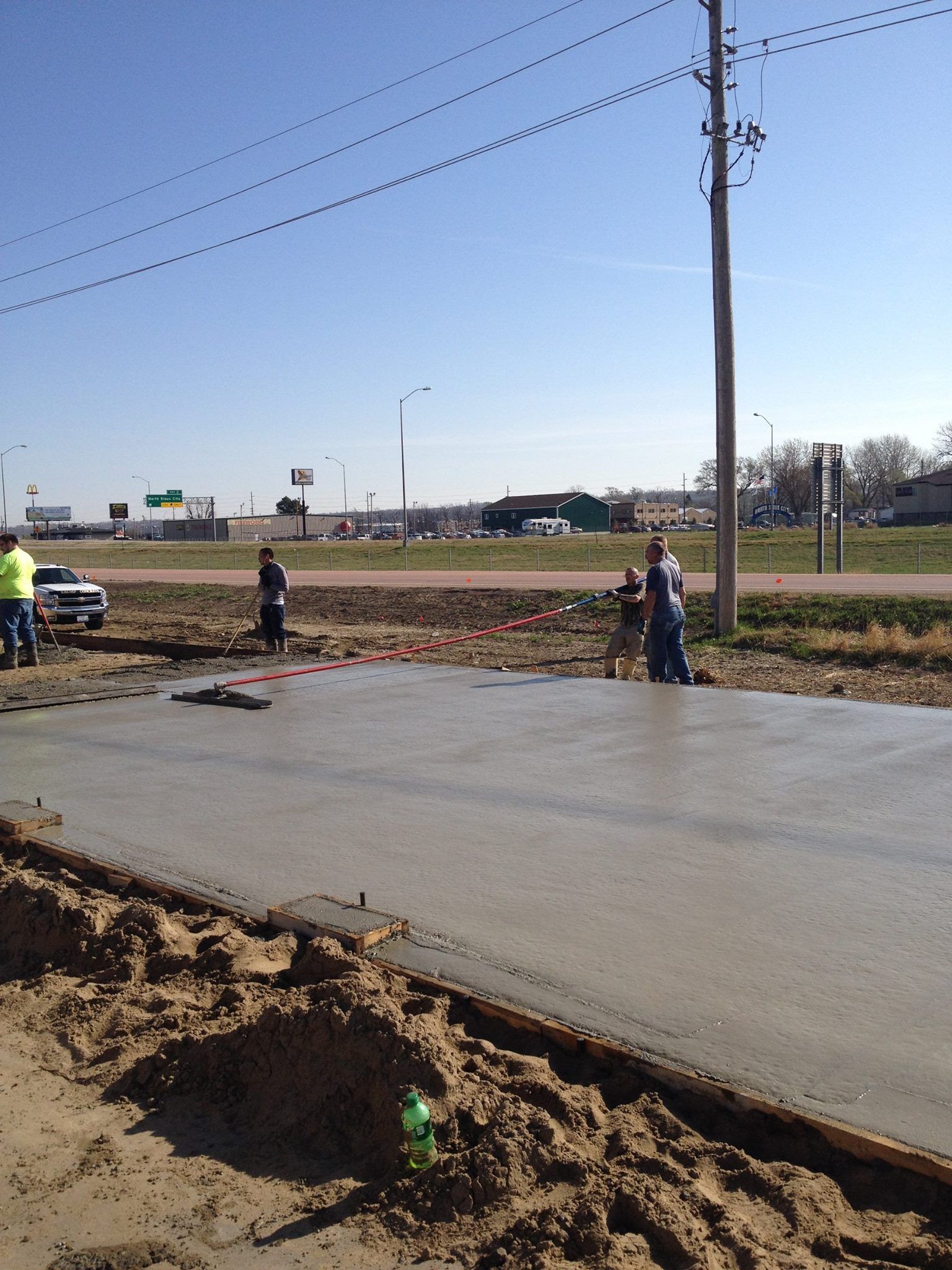 A group of construction workers are working on a concrete driveway