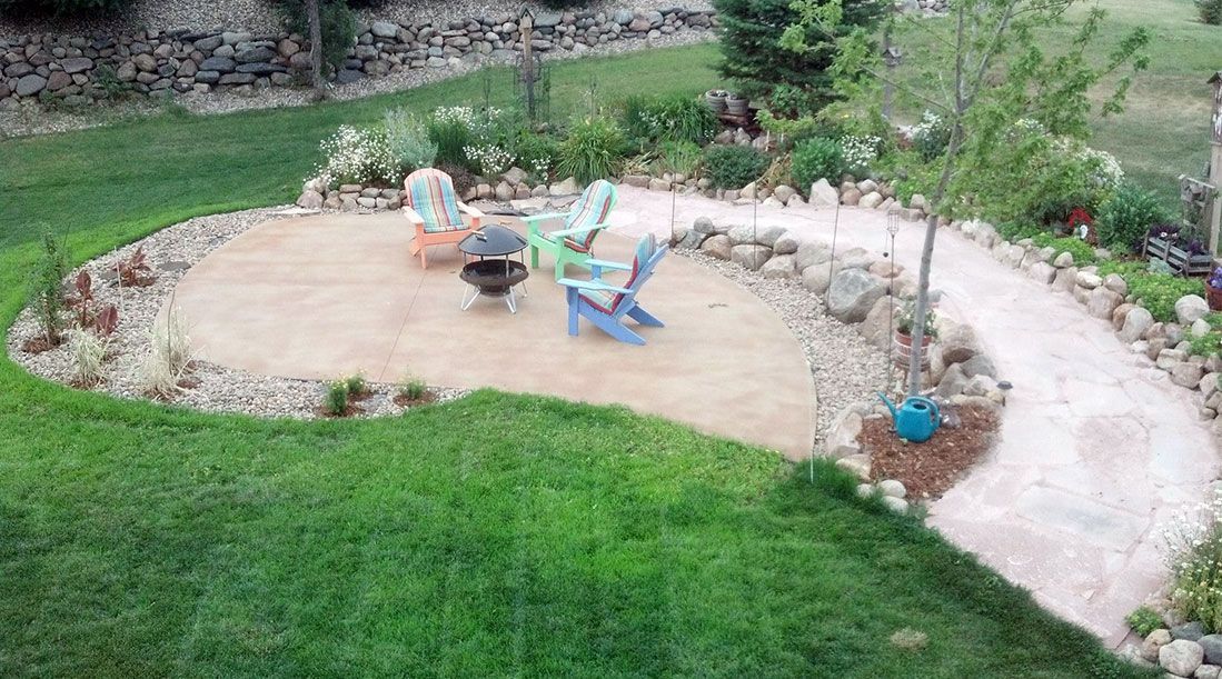 A patio with chairs and a fire pit in a backyard.