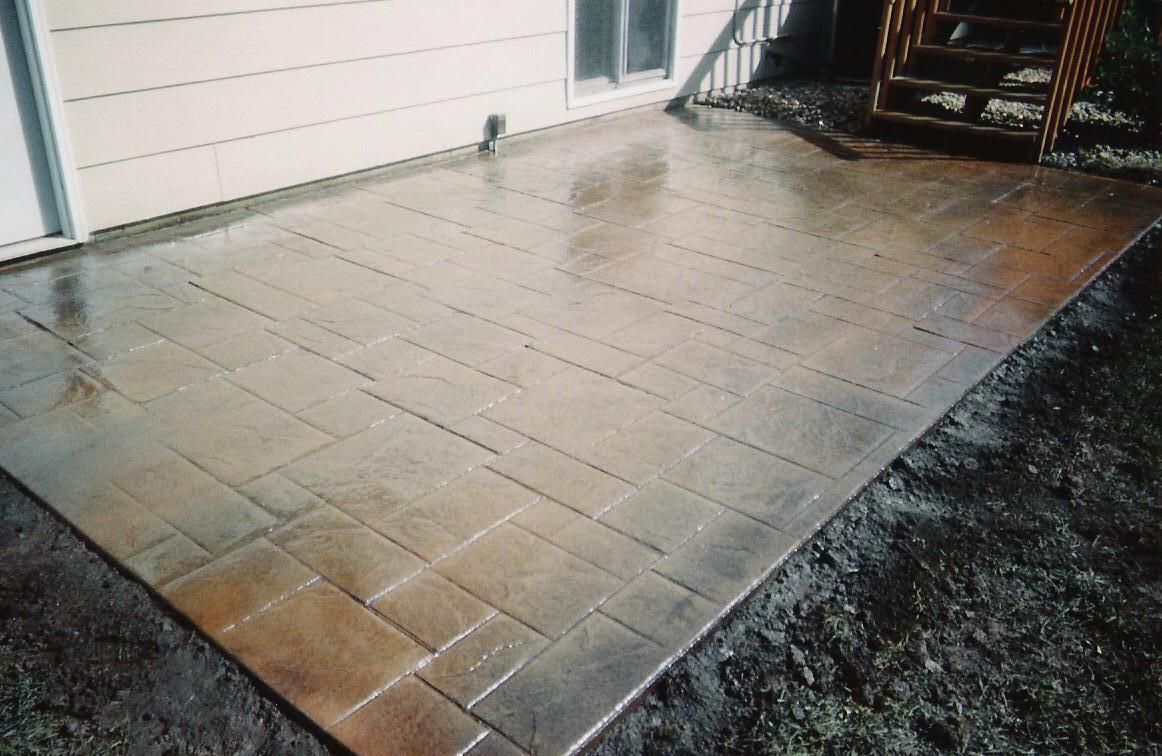 A patio with a staircase in the background and a house in the background.