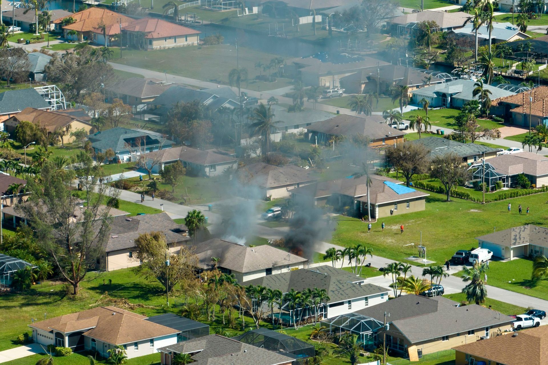 burning residential house on fire- with smoke and flames and firefighters extinguishing