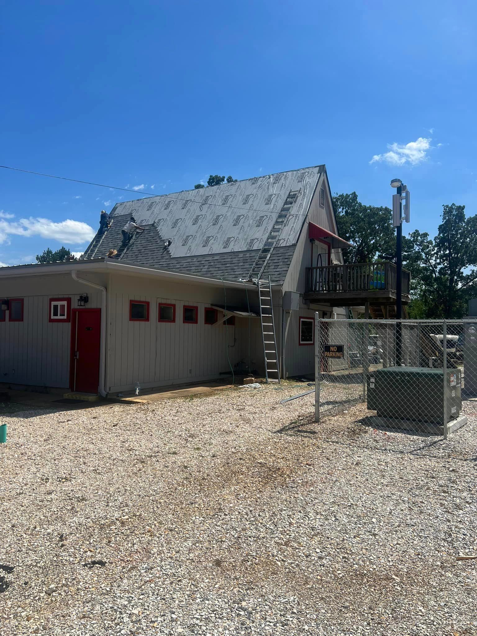 A white house with a red door is sitting on top of a gravel lot.