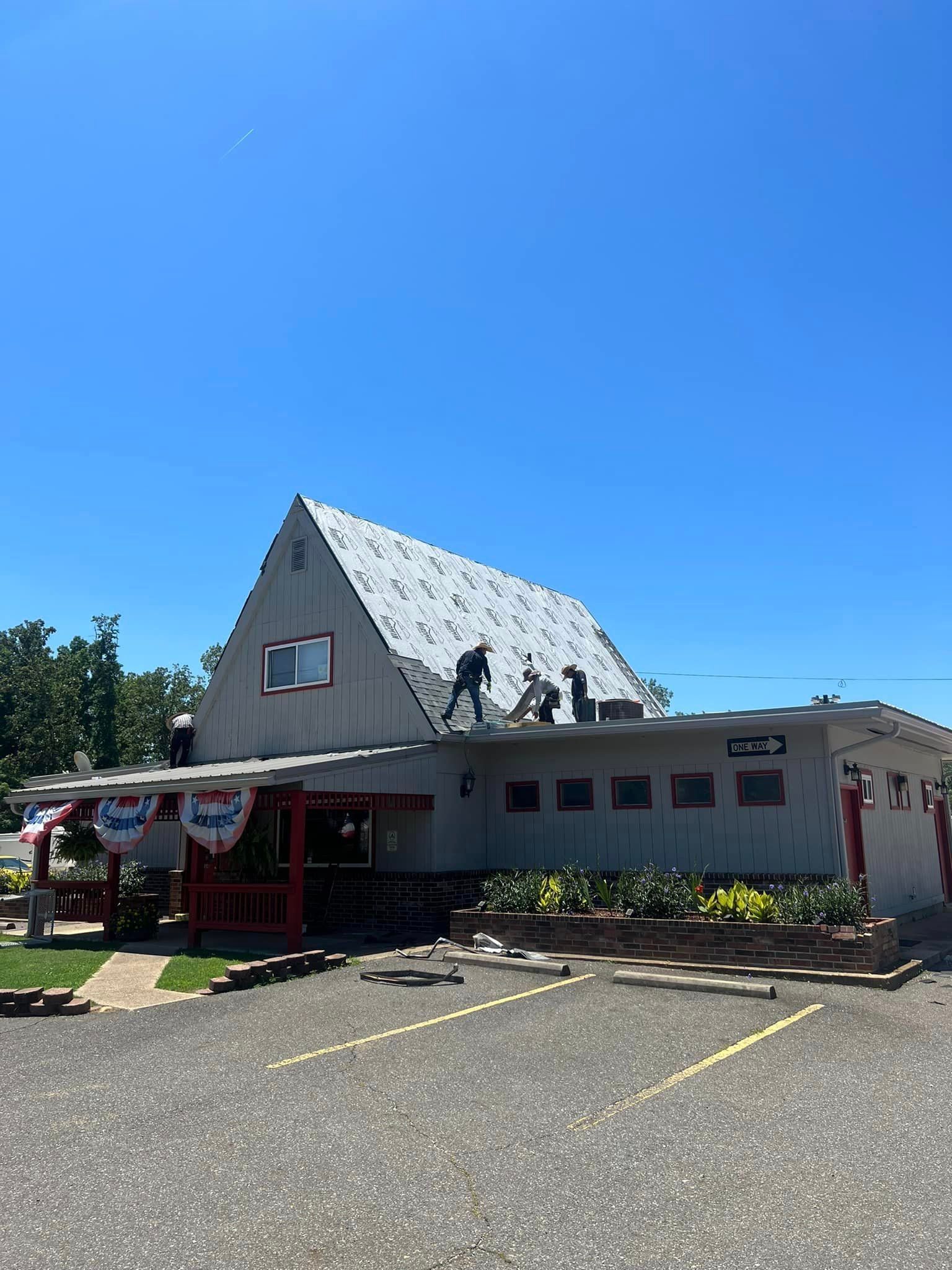 A large white building with a roof that is being fixed on a sunny day.