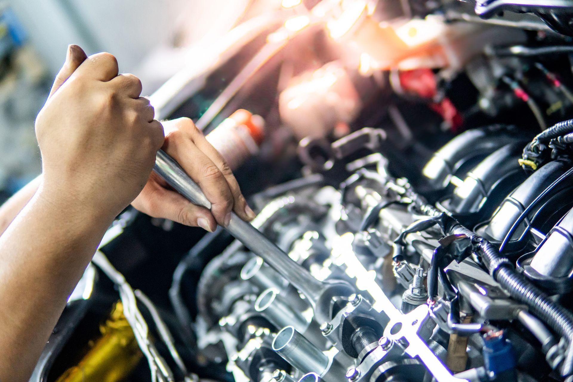 Person wearing gloves working on a car brake rotor and caliper in a garage.