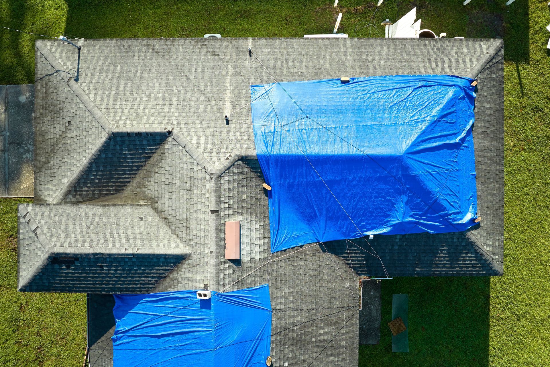 An aerial view of a house with a blue tarp on the roof.