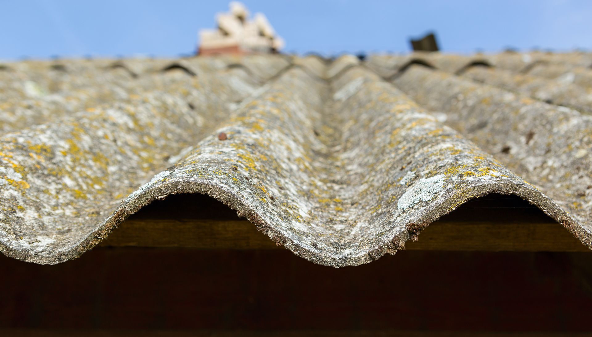 A close up of an asbestos roof with a blue sky in the background.