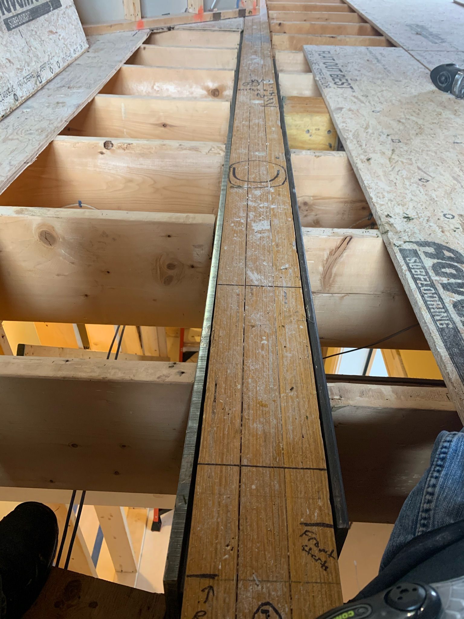 Wooden beam centered between joists in a construction setting.