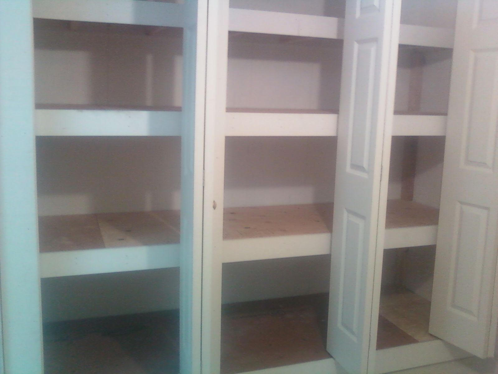 Empty white pantry with multiple shelves and two open doors.