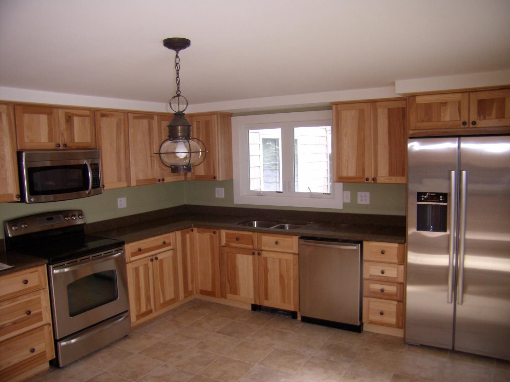 Kitchen with light wood cabinets, stainless steel appliances, and a hanging lantern.