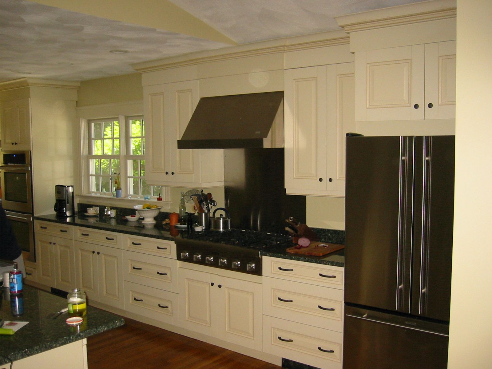 Cream-colored kitchen cabinets with dark countertops, stainless steel appliances, and a range hood.