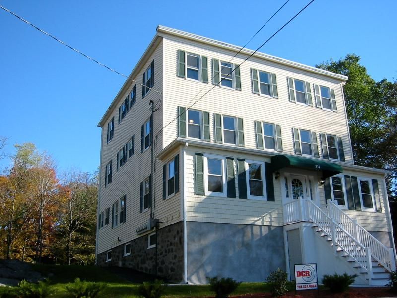 Multi-story light yellow building with green shutters and a white staircase.