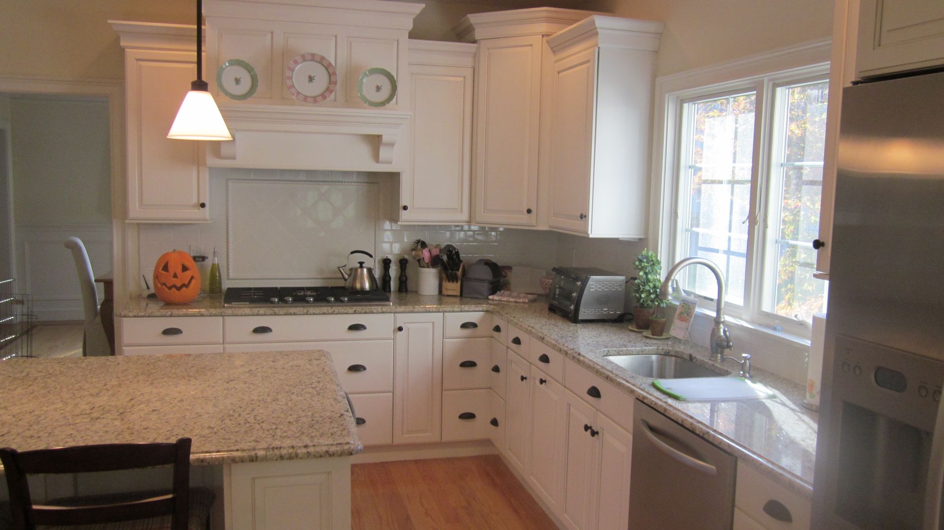White kitchen with granite countertops, stainless steel appliances, and a pumpkin.
