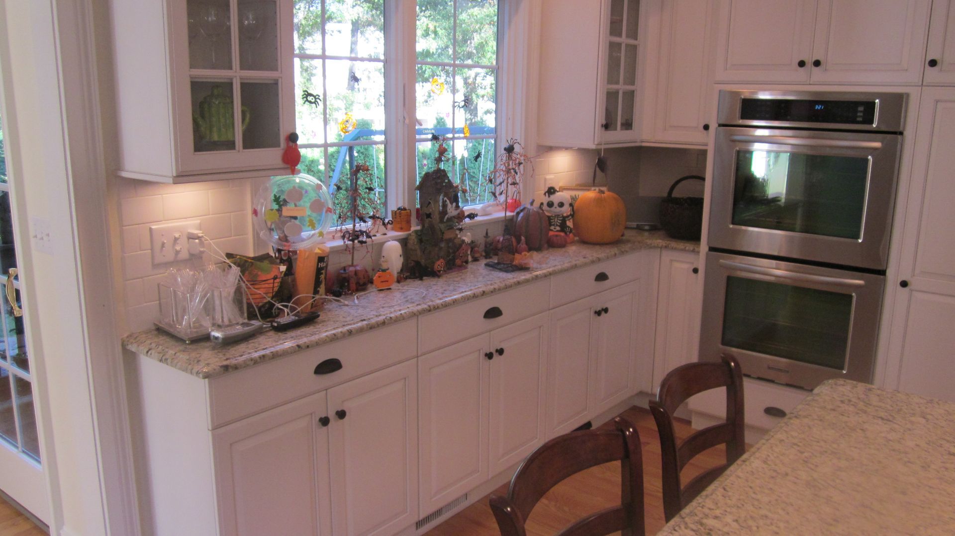 White kitchen decorated for Halloween with pumpkins and other decorations on the countertops.