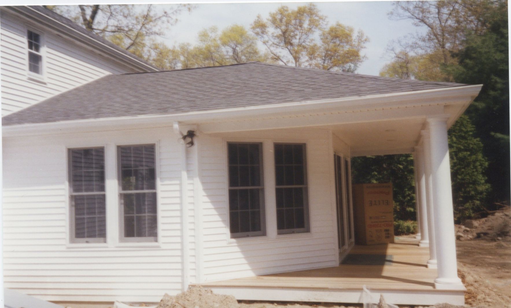 White house extension with windows, porch, and gray roof.