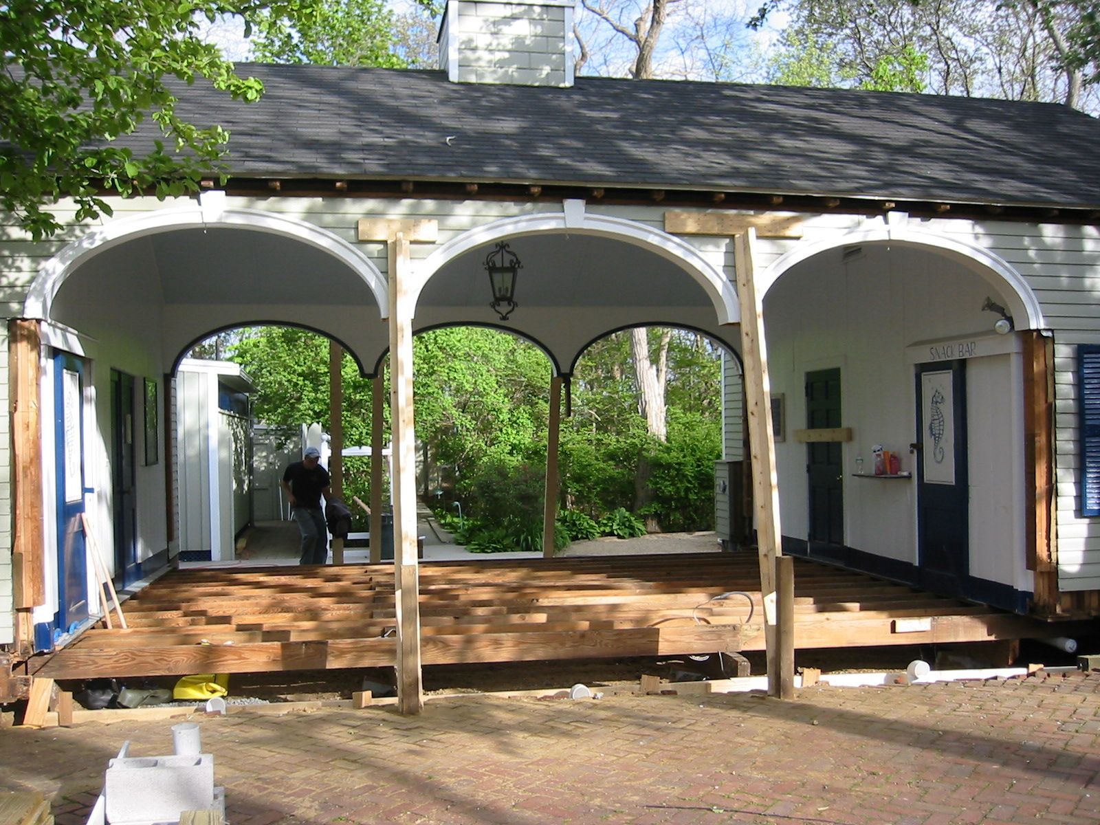 A porch with arched openings is under construction. Wooden supports hold up the roof.