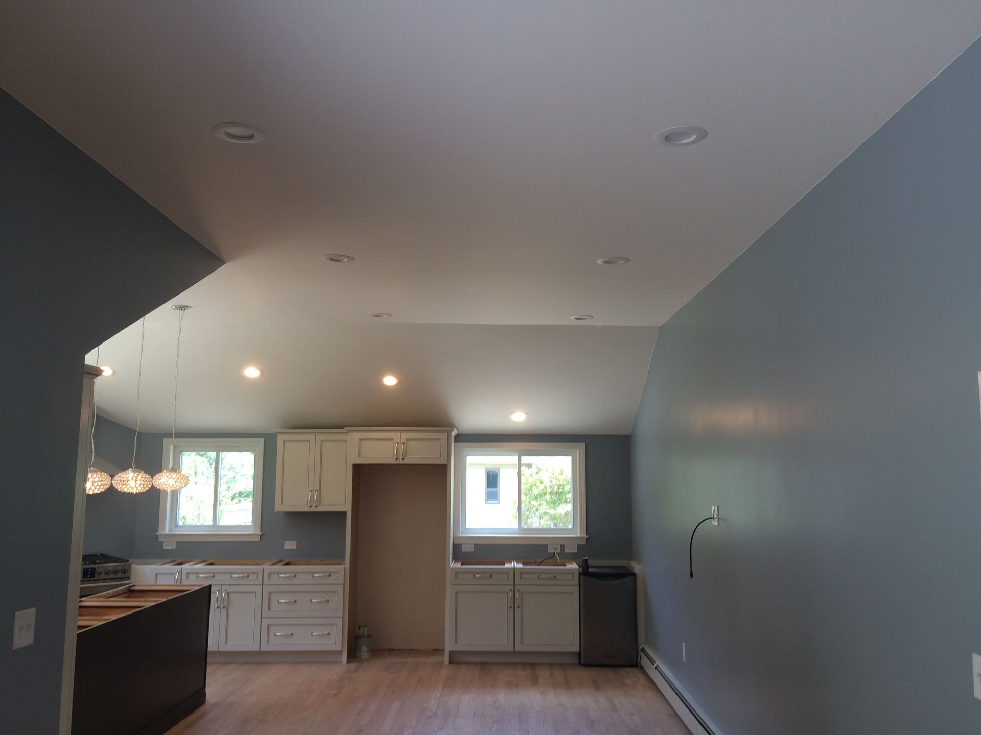 Newly renovated kitchen with white cabinets, gray walls, and recessed lighting.