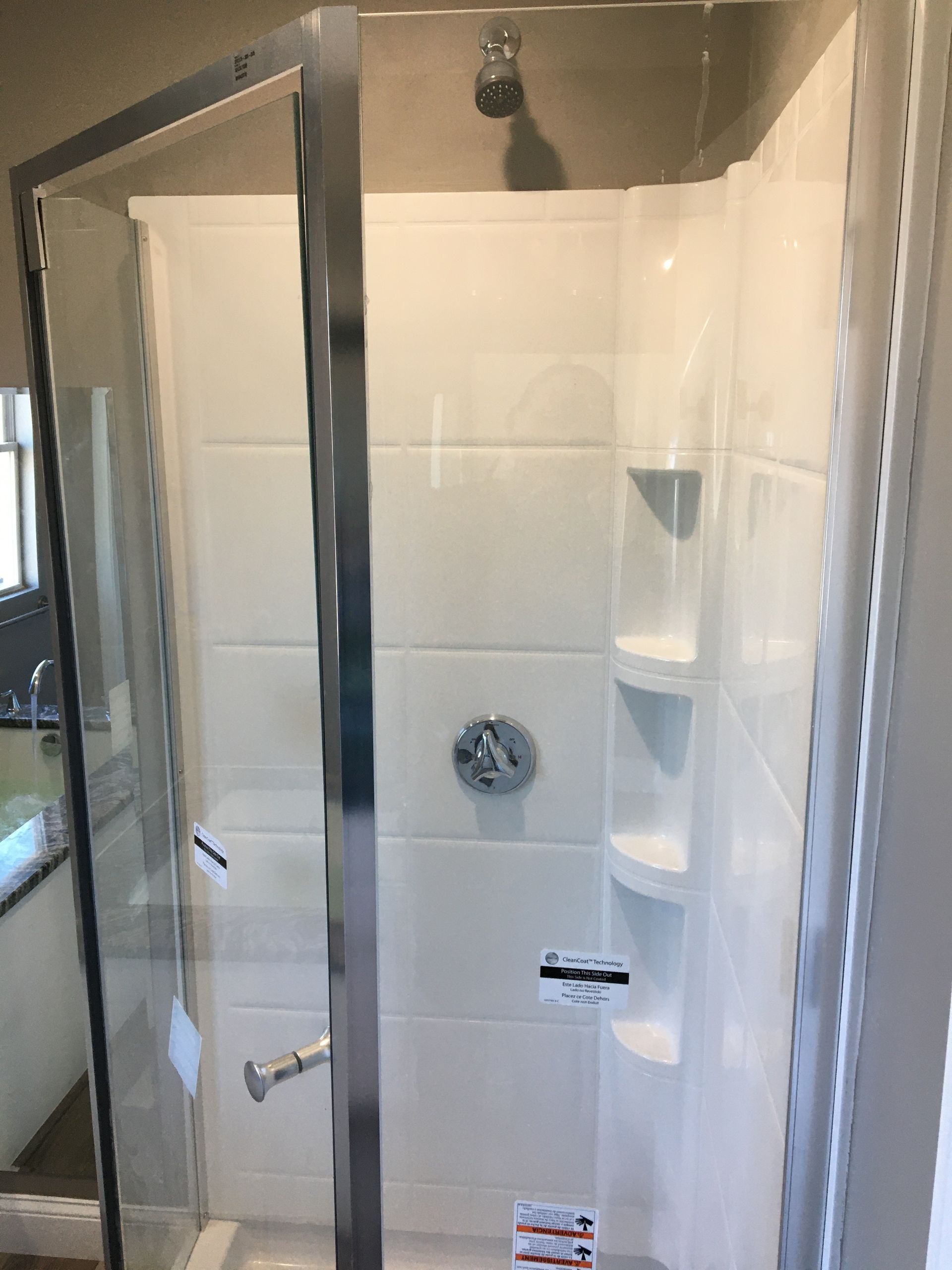 A white shower stall with a glass door and built-in shelves.