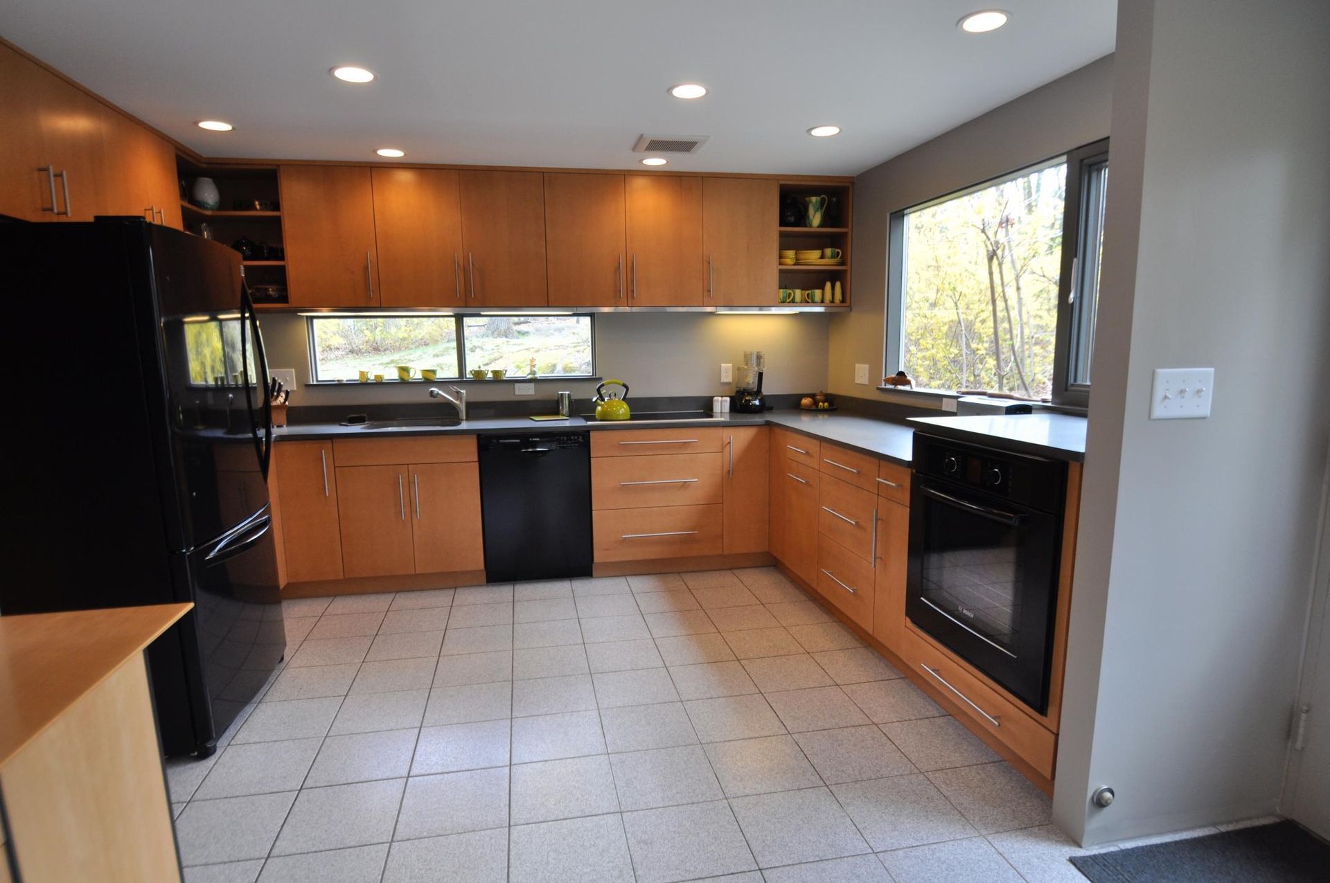 Kitchen with light wood cabinets, black appliances, and tiled floor.