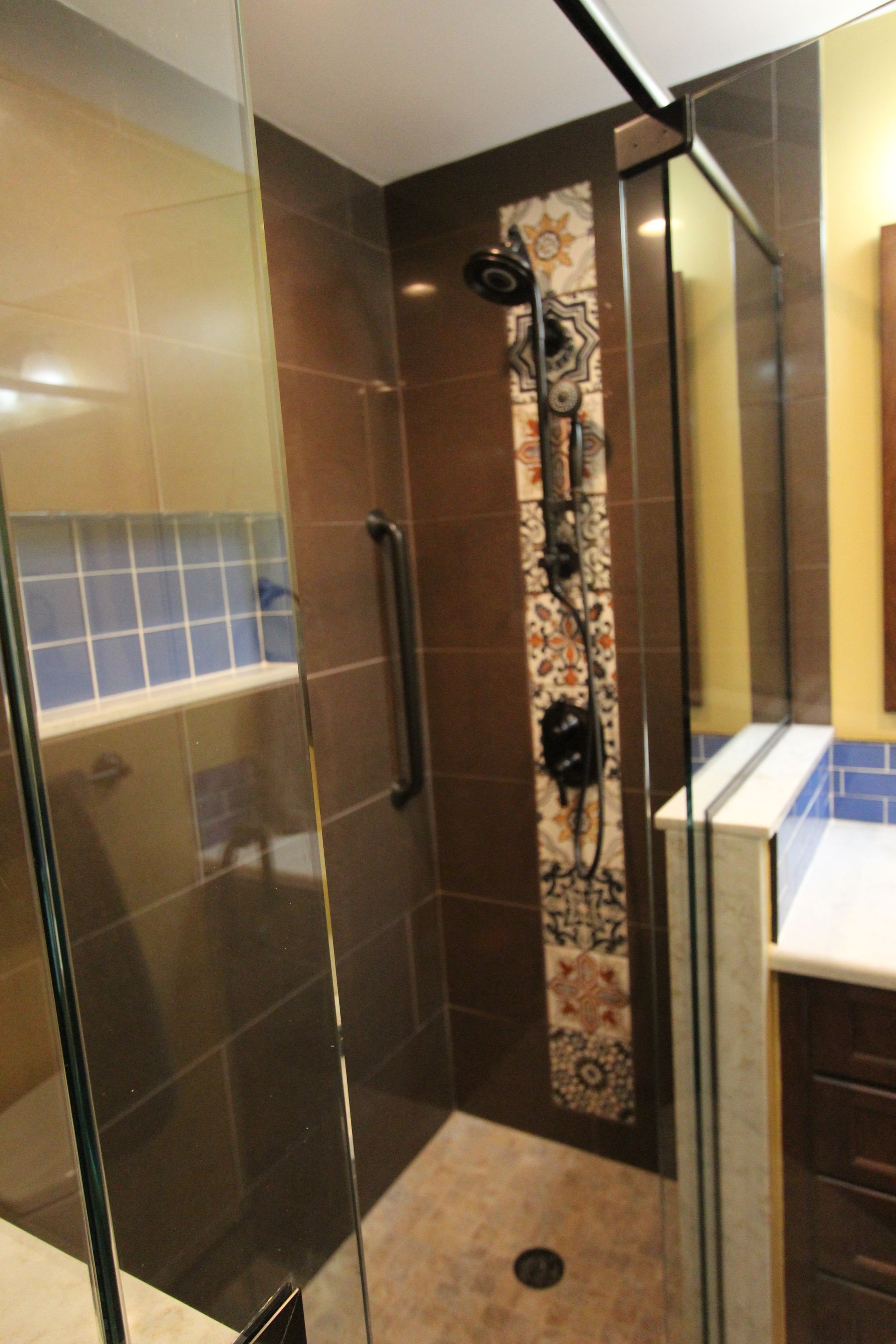 Bathroom with brown tile shower, decorative tile strip, and a grab bar.