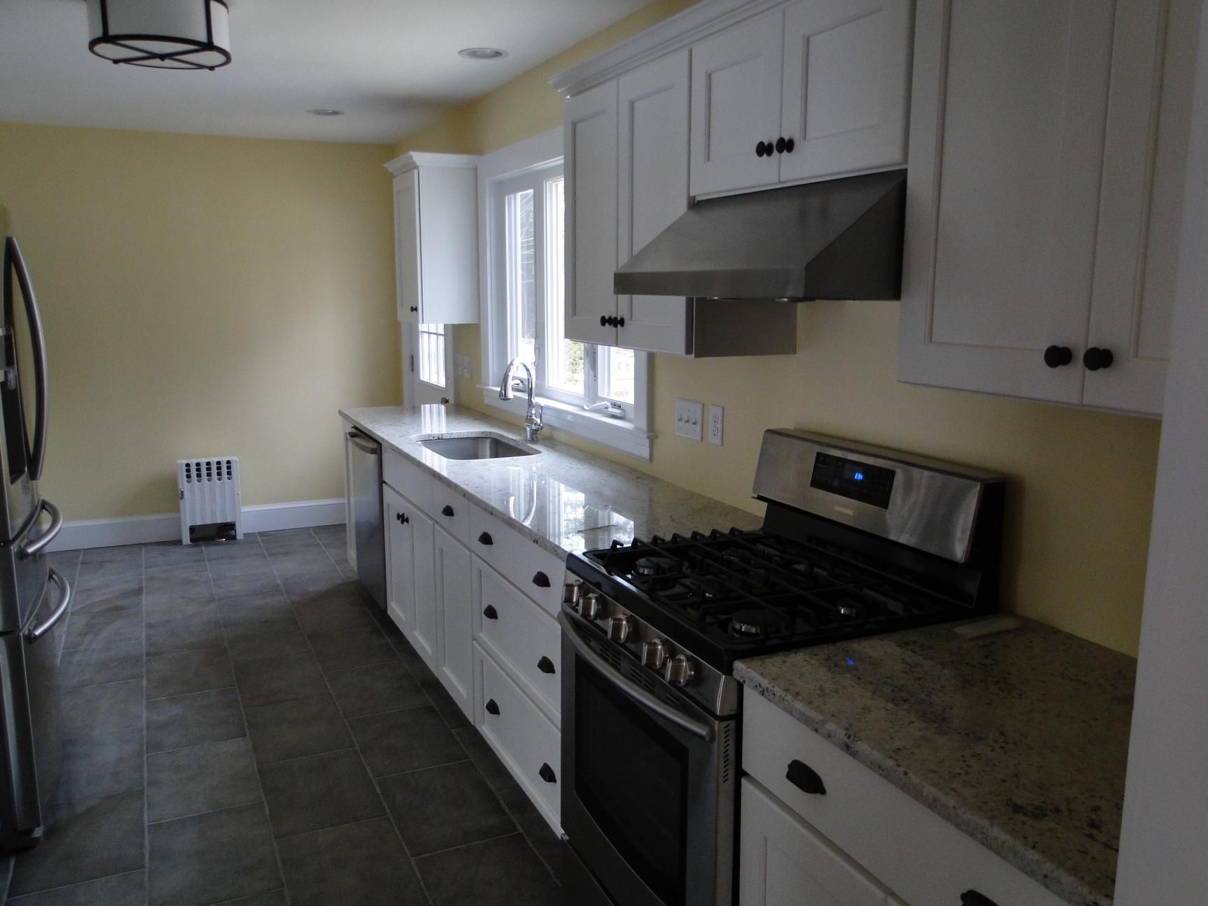 Kitchen with white cabinets, stainless steel appliances, and yellow walls.