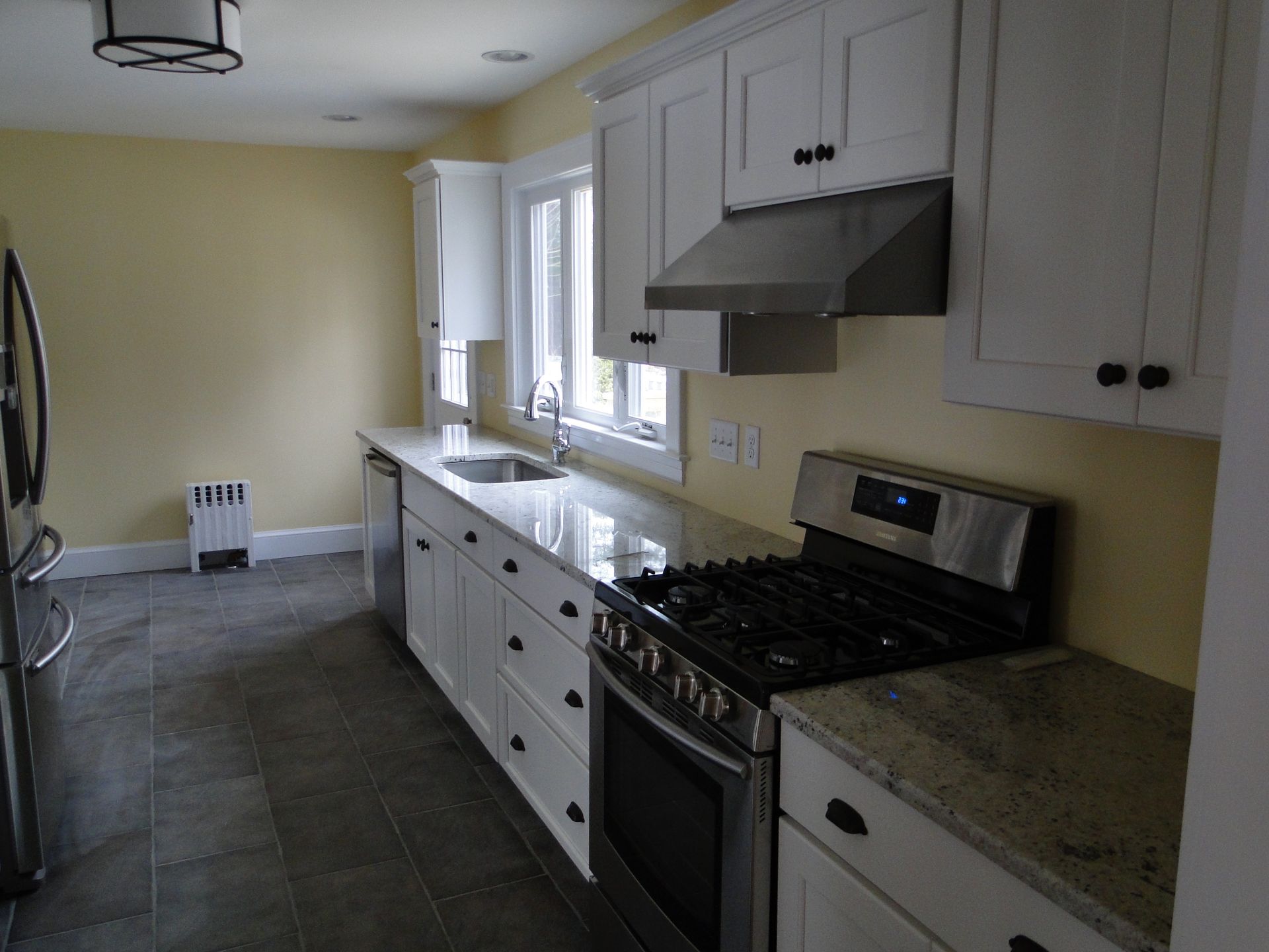 Kitchen with white cabinets, stainless steel appliances, and granite countertops; yellow walls.