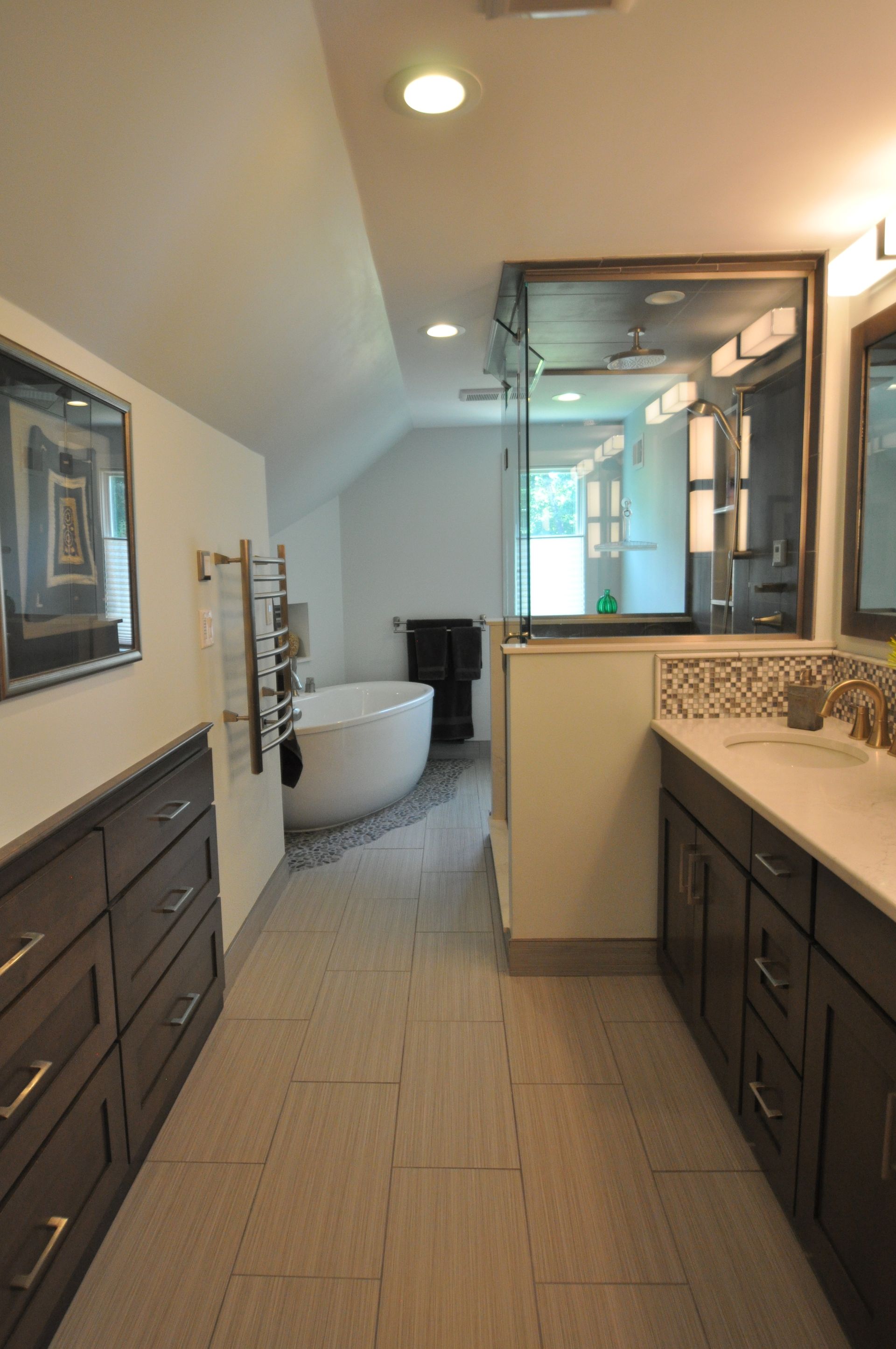 Spacious bathroom with dark cabinets, a freestanding tub, and a large mirror.