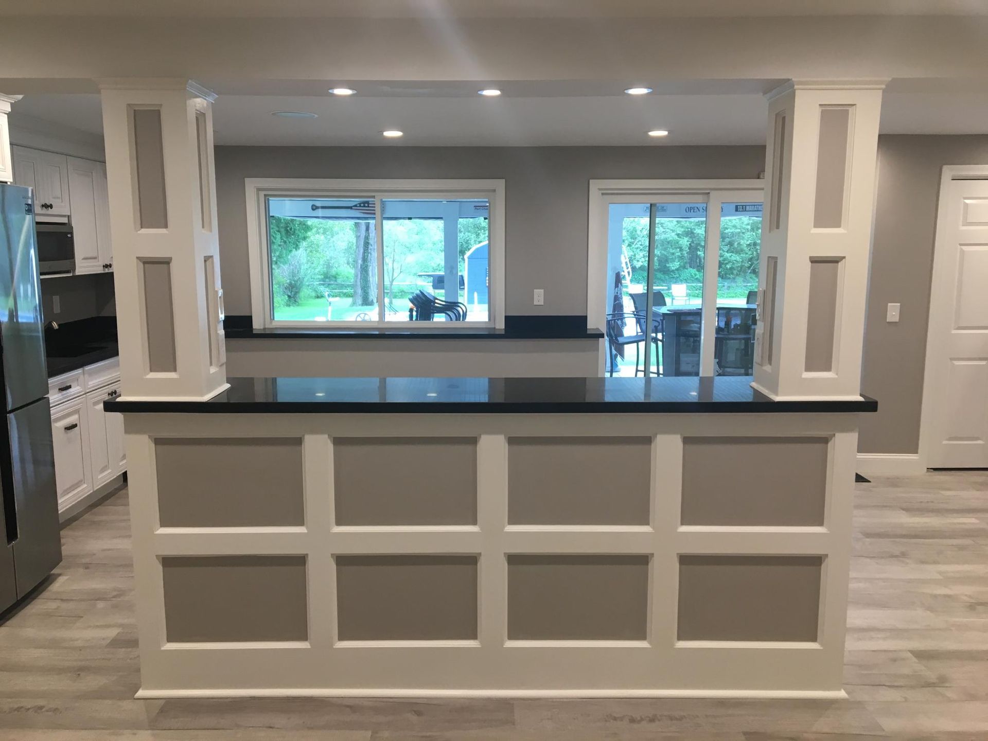 Kitchen island with black countertop, white trim, gray panels, and two supporting columns.